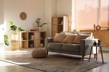 Interior of stylish living room with grey sofa, bookshelves and books © Pixel-Shot