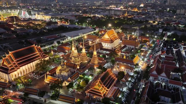 Bangkok, Thailand: Aerial night view of Wat Pho Thai Buddhist temple complex (Temple of the Reclining Buddha) in heart of Thai capital city, Grand Palace on horizon - landscape drone panorama