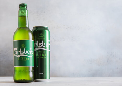 LONDON,UK - DECEMBER 11,2025: Aluminium tin and bottle of Carlsberg lager beer on light table background.