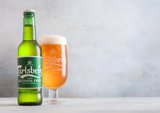 LONDON,UK - NOVEMBER 28,2025: CarlsbergAlcohol Free lager beer bottle and original glass on light table background.