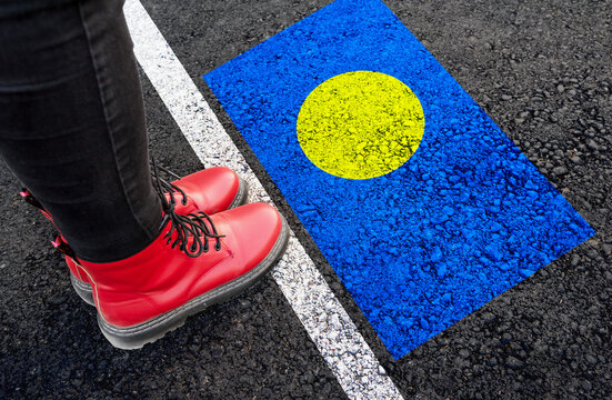 a woman with a boots standing on asphalt next to flag of Palau and border
