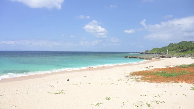 青空とエメラルドグリーンの海が広がる美しい白い砂浜の風景