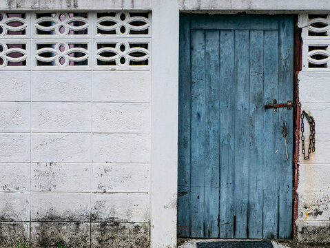 Weathered Blue Wooden Door with Ornate White Breeze Block Wall