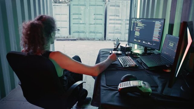 Young male coder committing credit card fraud inside a shipping container hideout