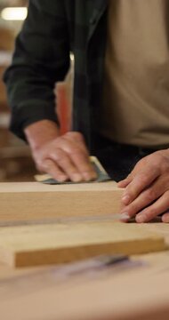 Hands, sandpaper and man with wood for carpenter job, woodwork manufacturing and warehouse. Person, productivity and process for smooth texture in workshop with custom or handmade timber furniture