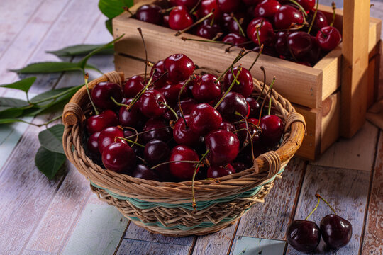 Fresh cherries in wicker basket and wooden crate on rustic table