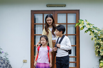 Fototapeta premium Mother sending children off to school, preparing them for the new academic year with backpacks and encouraging words, fostering independence and growth in their education journey