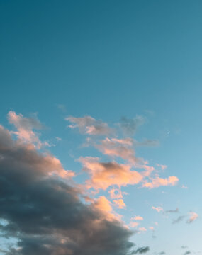 Blue evening sky with pink sunset clouds and dark storm cloud.