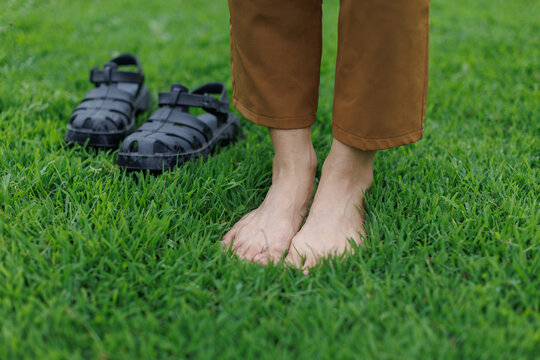Person's bare feet are planted firmly on fresh green grass, experiencing grounding and a close connection to nature, symbolizing relaxation, freedom, and personal wellness outdoors