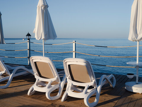 Sun loungers and umbrellas on a wooden beach pier