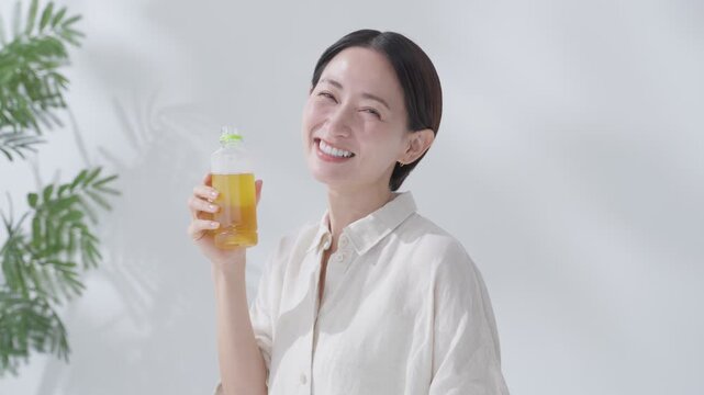 水分補給でペットボトルの緑茶を飲む女性