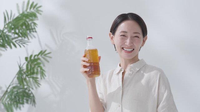 水分補給でペットボトルの緑茶を飲む女性