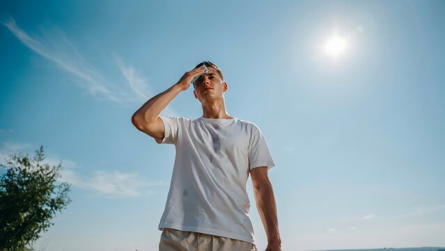 Tired man wiping his forehead with a handkerchief beneath the blazing summer sun