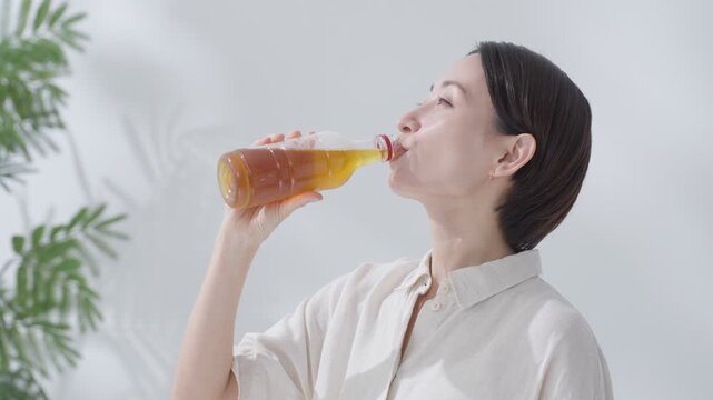 水分補給でペットボトルの緑茶を飲む女性