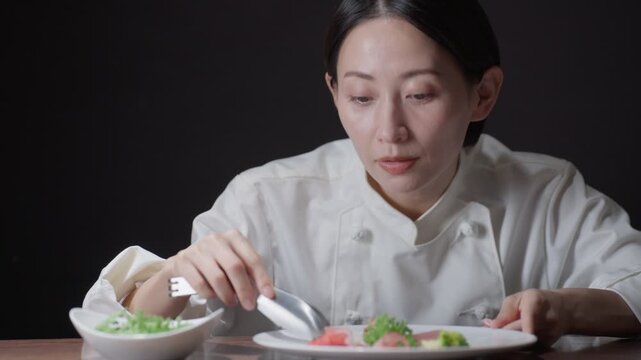 料理の盛り付けをする女性シェフ