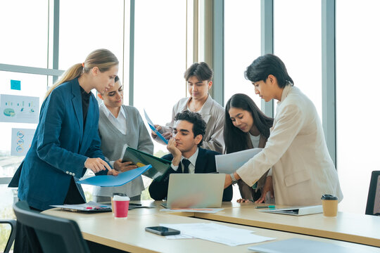 Business team presenting documents to an overwhelmed manager during a demanding office meeting. Heavy workload, workplace stress, project deadlines, leadership challenges and corporate collaboration.
