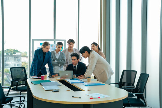 Diverse business team gathered around a laptop during a strategy meeting. Colleagues collaborate on project planning, business analysis and decision making in a modern corporate office.