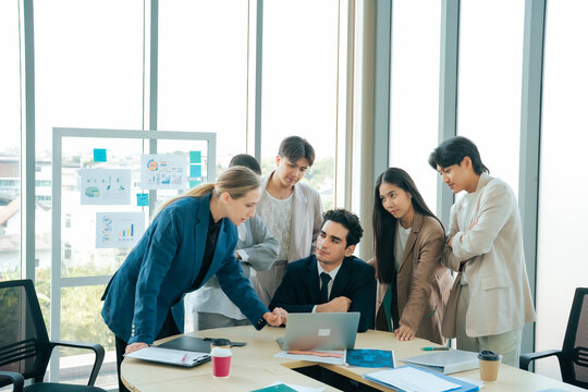 Team members discussing project progress around a laptop during a collaborative business meeting. Professional teamwork, strategic planning and communication support successful project development.