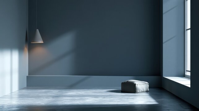Minimalist empty room interior with gray concrete floor and walls soft natural light streaming through large window with single gray cushion and hanging lamp