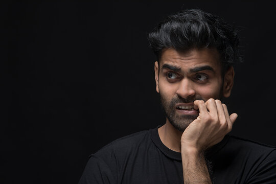 Confused young man biting his nail