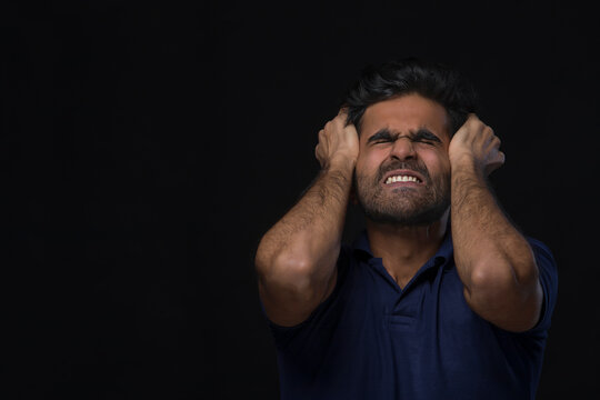 closeup of an angry man holding his head