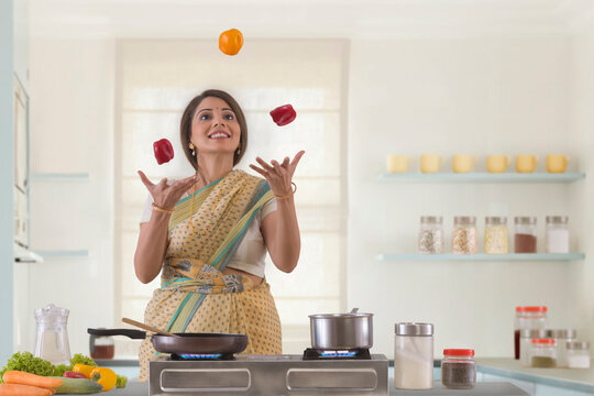 woman in kitchen juggling capsicums