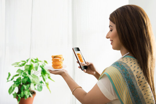 woman clicking photo of sweet dish in hand