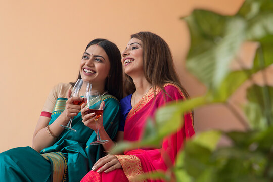 women in saree having a drink together