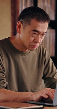 Asian man, remote work or laptop in home for business, editing article or schedule for productivity. Mature writer, tech or serious with typing for publishing deadline, fact checking or task in Japan