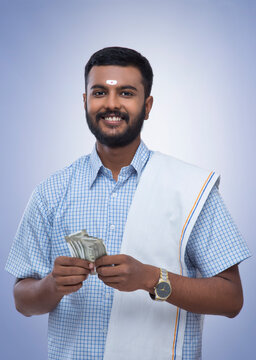 south indian man holding money and smiling at the camera