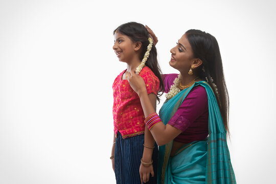 south indian woman putting gajra in her daughters hair