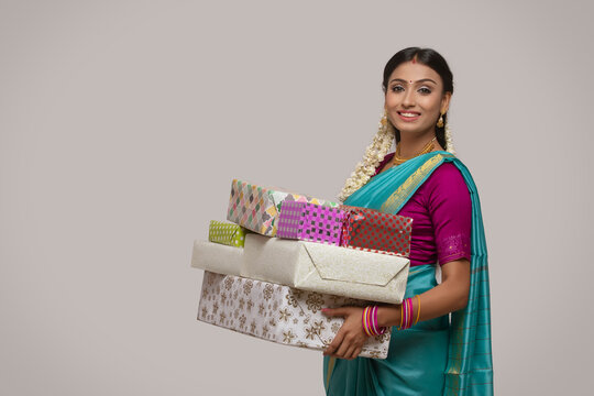 south indian woman holding gifts and smiling at the camera