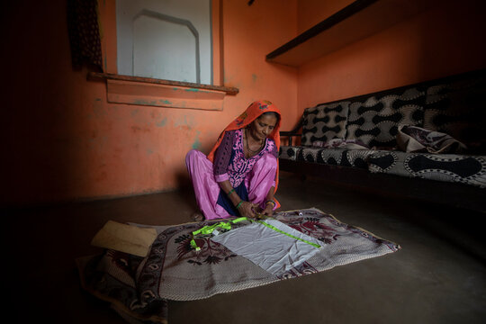 Old woman measuring sides of a cloth 