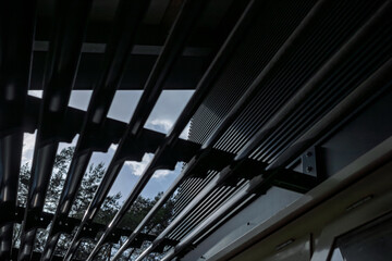 Fototapeta premium Abstract low-angle view of a black steel louvered canopy structure against a bright sky with clean modern lines.