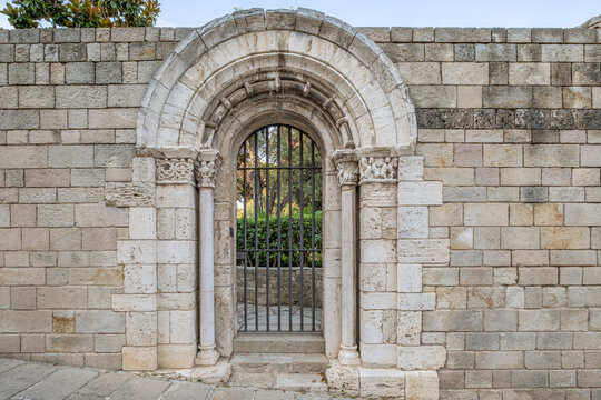 Romanesque Stone Archway Gate with Iron Gate in Stone Wall in Barcelona, Medieval Architecture