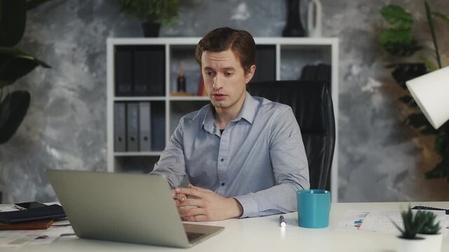 Young male project manager communicating with partners via video call on laptop