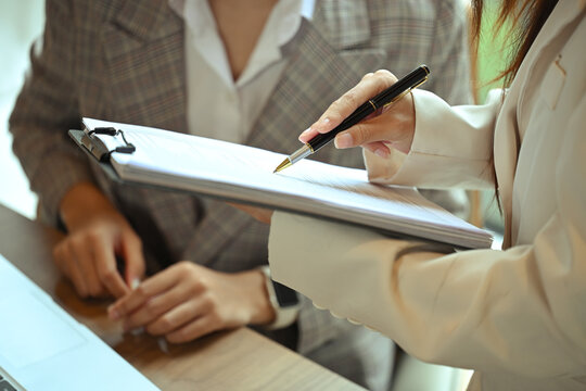 Two businesswomen wearing formal suit analyzing financial documents in the office