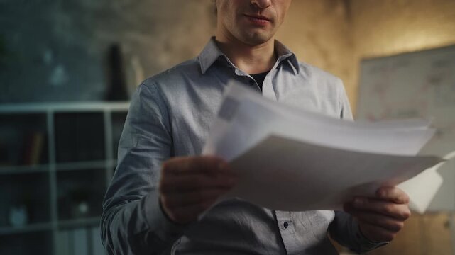Young male accountant reading documents in office, analyzing company income