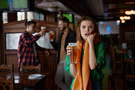 An apprehensive woman in cozy bar observing friends celebrating with lively chatter