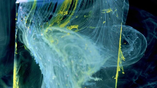 Near-macro view of painted object at right shedding vivid yellow and pale blue pigment into clear aqua liquid, producing defined vertical streaks