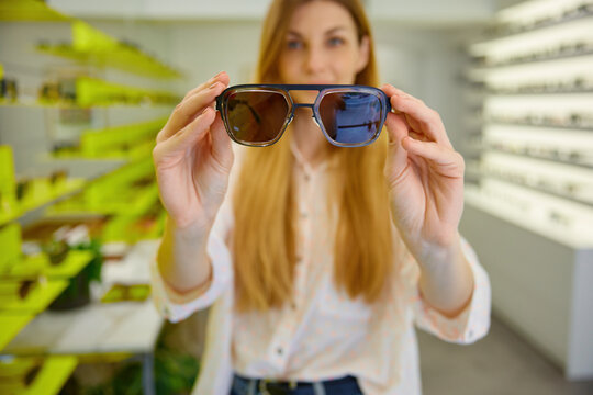 Young woman presenting stylish sunglasses in boutique