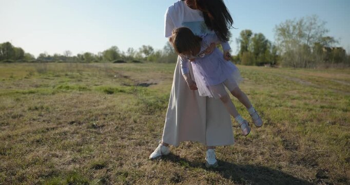 Young mother with child daughter spend time playing enjoying nature. 4K 10-bit