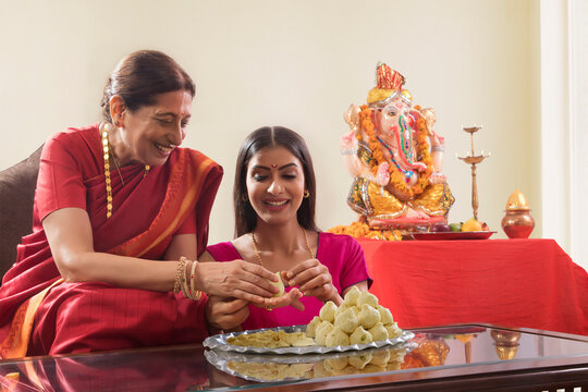 Mother in law teaching daughter in law how to make modaks on the occasion of Ganesh Chaturthi