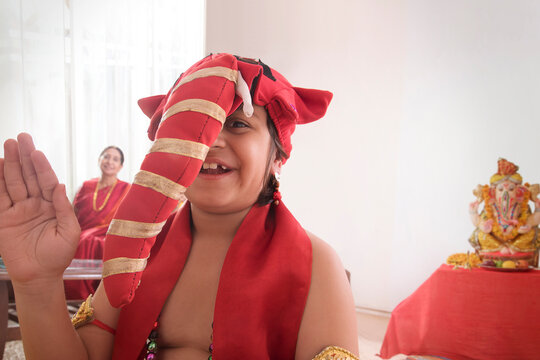 Child sitting dressed up like Ganpati in living room