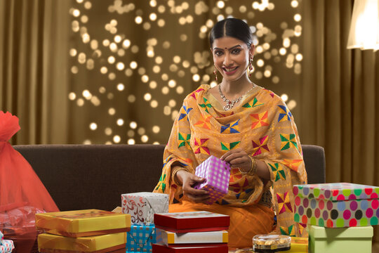 young woman sitting on a sofa holding gift box