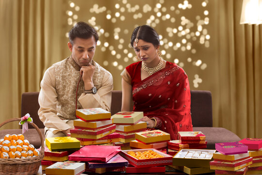 upset young couple sitting on a sofa with present on diwali