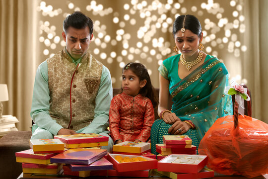 upset family sitting on a sofa with presents on diwali