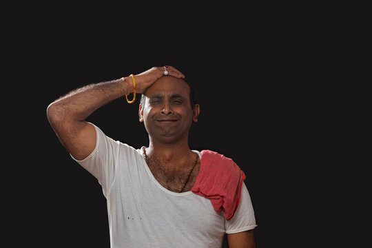 Depressed Indian farmer standing and holding his head in disbelief