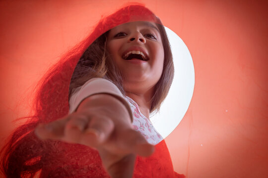 Close up of hand of a smiling girl picking something from an orange container