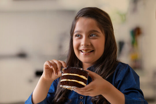 Happy girl eating a chocolate pastry looking away